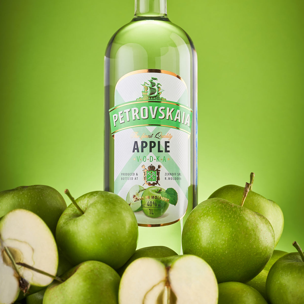 Petrovskaia Apple premium Vodka 1 liter fles met hele en gesneden appels tegen een groene achtergrond.