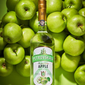 Petrovskaia Apple premium Vodka 1 liter fles liggend tussen verse groene appels.