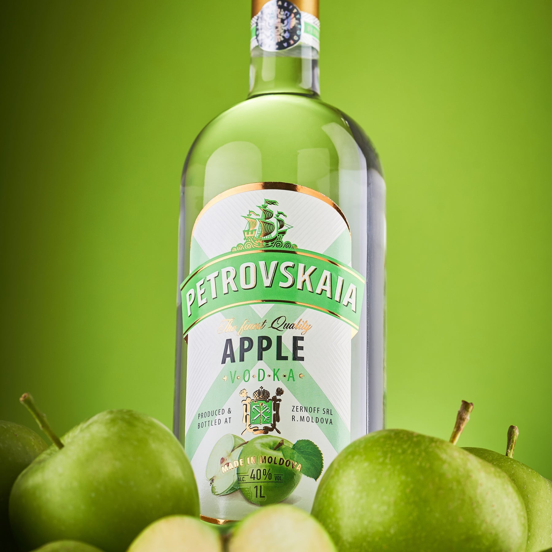 : Petrovskaia Apple premium Vodka 1 liter fles omringd door groene appels tegen een groene achtergrond.