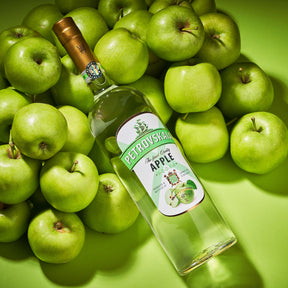 : Petrovskaia Apple premium Vodka fles schuin liggend tussen groene appels.