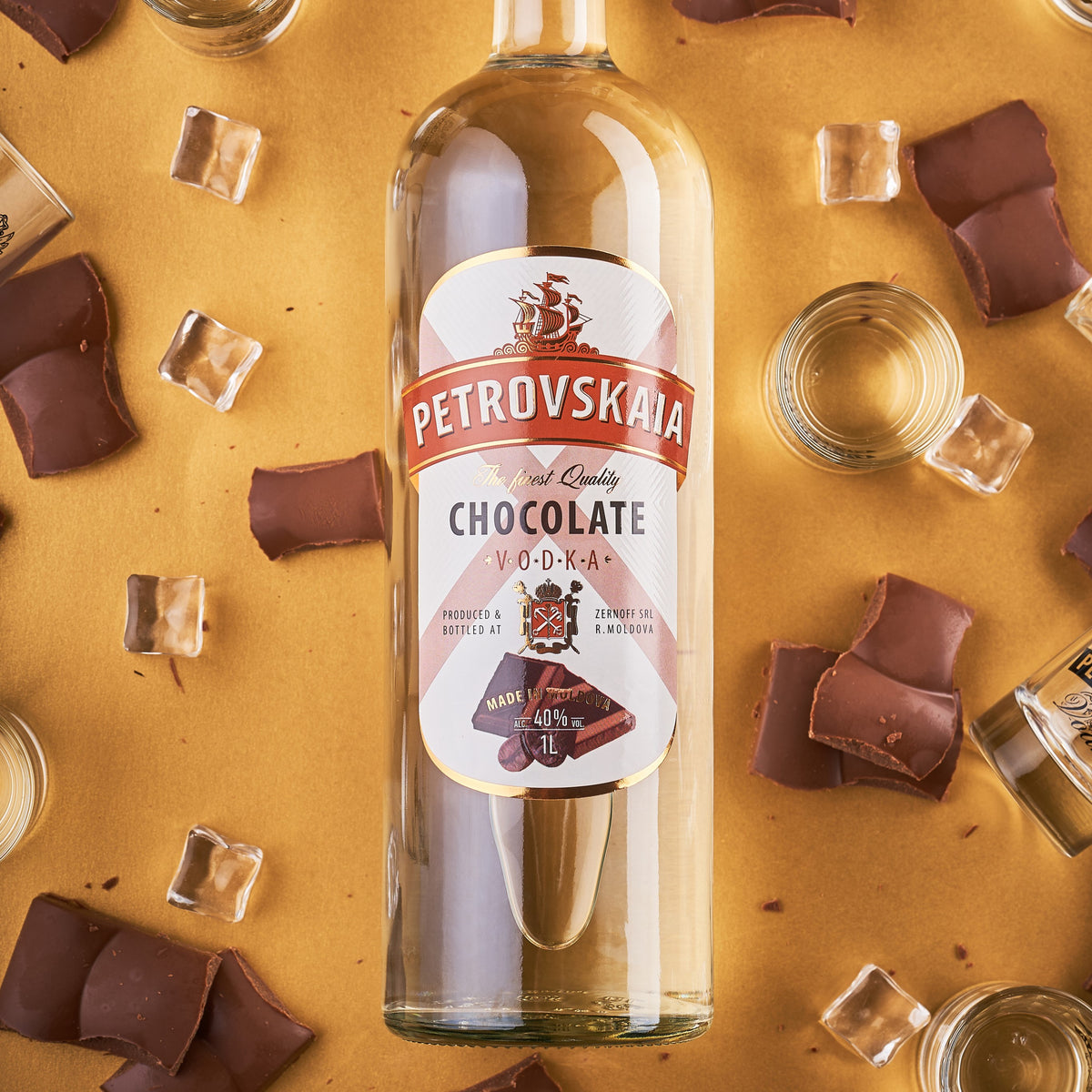 Petrovskaia Chocolate Vodka 1 liter fles omringd door stukjes chocolade en ijsblokjes op een gouden achtergrond, premium drank