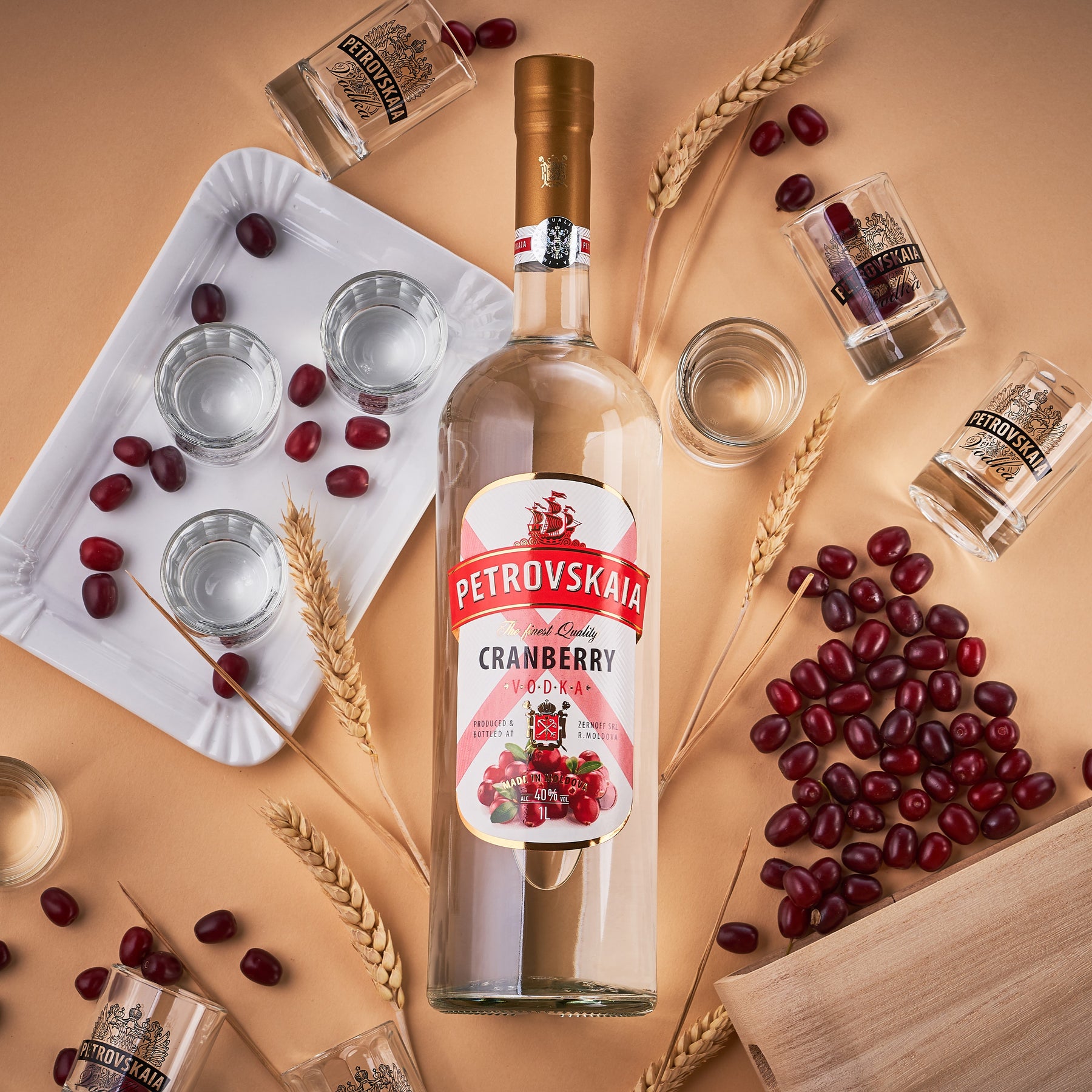 Petrovskaia Cranberry Vodka 1 liter fles liggend op een warme beige-oranje achtergrond met verse granen, cranberries en veenbessen, kwaliteit vodka.