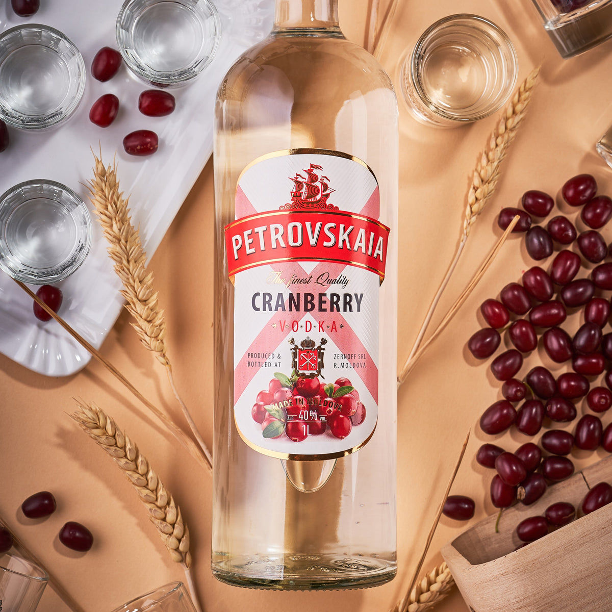 Petrovskaia Cranberry Vodka 1 liter fles omringd door verse granen, cranberries en veenbessen op een warme beige-oranje achtergrond, premium drank.