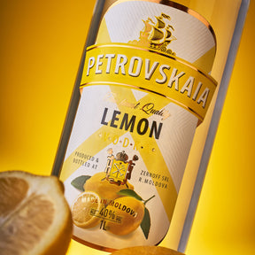 Ingezoomde Petrovskaia Lemon Vodka 1 liter fles met label en een halve citroen in beeld, luxe citroenwodka.