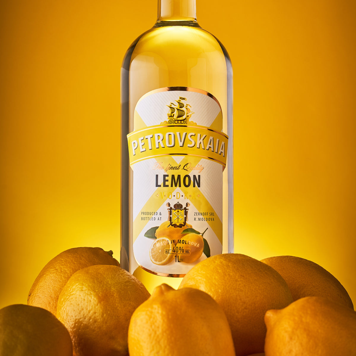 Petrovskaia Lemon Vodka 1 liter fles omringd door hele citroenen op een gele achtergrond, verfrissende citroenwodka.