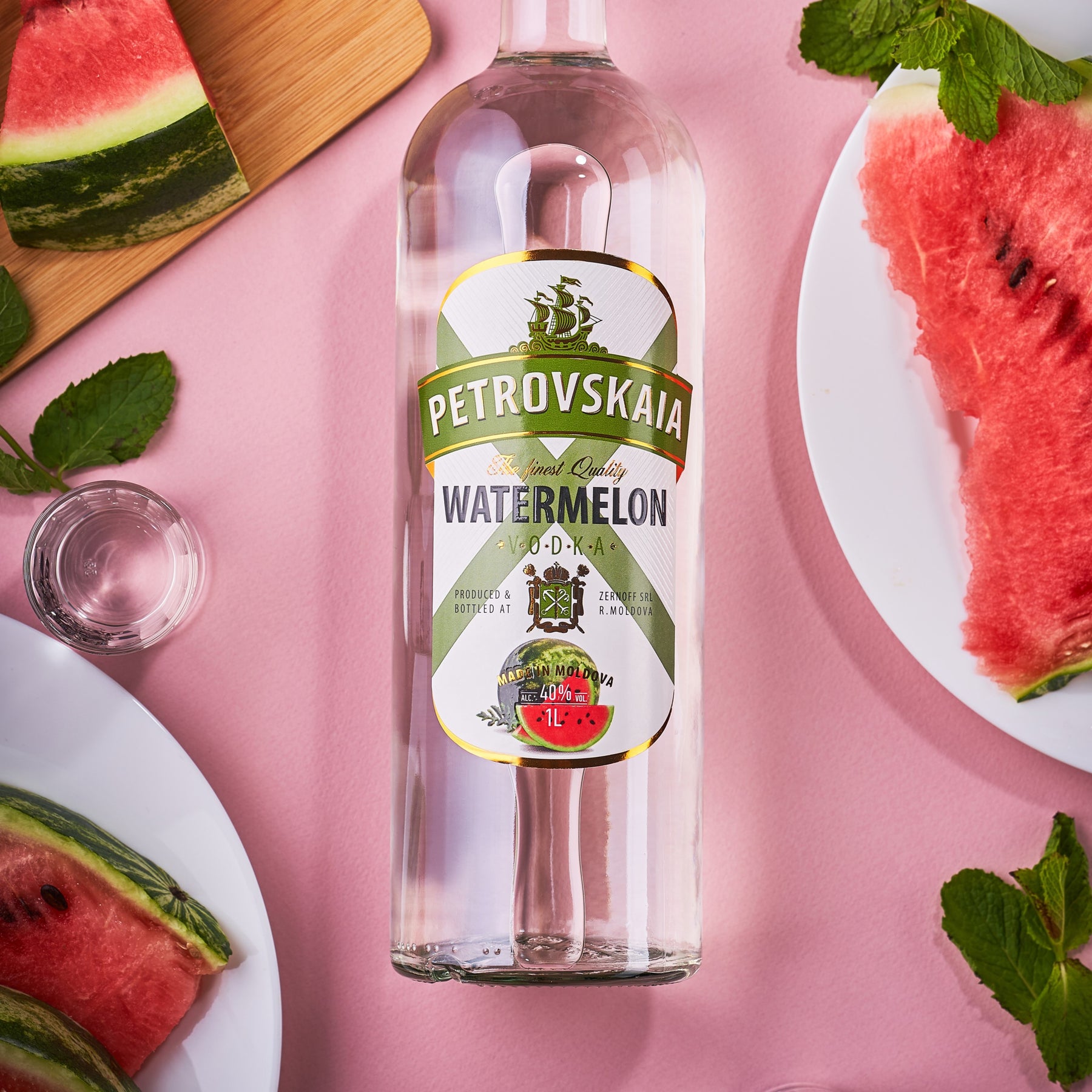 Petrovskaia Watermeloen Vodka 1 liter fles met stukken watermeloen, munt en een shotglaasje in beeld, verfrissende watermeloenwodka, premium watermeloenwodka.